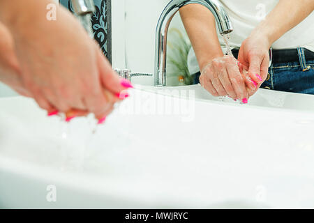Caring for personal hygiene. Hand washing, dirty hands disease, medicine, viral hepatitis concept. The woman washes her hands, reflected in the mirror Stock Photo