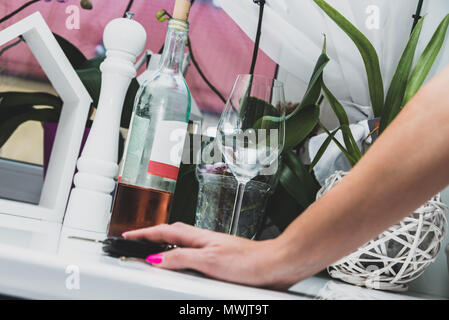 The woman is trying to open a bottle with wine, alcohol. Longing for alcohol, for wine. Alcohol problems concept. Drinking wine, party, fun, lonelines Stock Photo