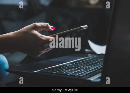 Transactions on your mobile phone and laptop. The woman checks the bank code, information needed to use the laptop. Online shopping, bank transfers, b Stock Photo