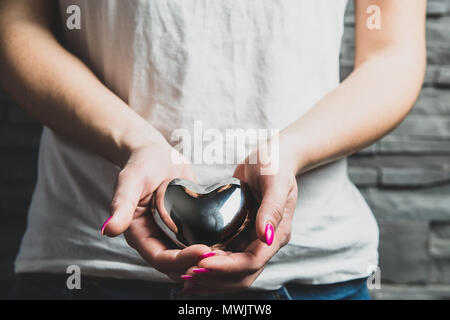Female hands hold a metal heart, a concept of love. Valentine's Day, Valentine's day. Gifts for occasions, love, showing love and cordiality. Stock Photo