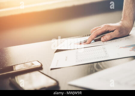 Businessman at work. The man analyzes the information, checking the charts. Analysis of expenditure reports, costs. Home office, work in the office. T Stock Photo