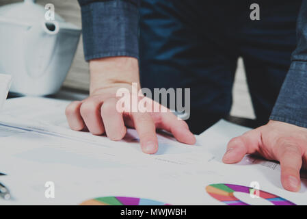 Businessman analyzing the data on desk. Man leaning over reports and graphs. Expenses and profits. Balance of costs. The concept of running a business Stock Photo