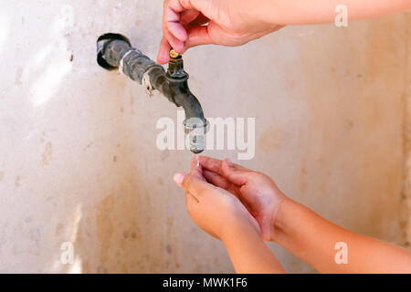 Woman hand open water tap and child washing his hands. Close-up. Stock Photo