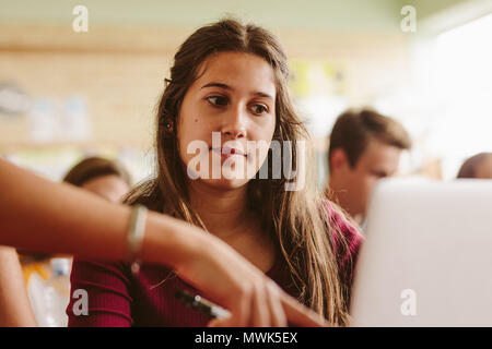 Close up of beautiful female student listening to the instruction from the teacher. Woman looking at laptop screen with lecturer pointing. Stock Photo