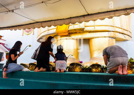 Believers praying in front of the feet of a Big Standing Buddha in Wat Intharawihan Temple Stock Photo