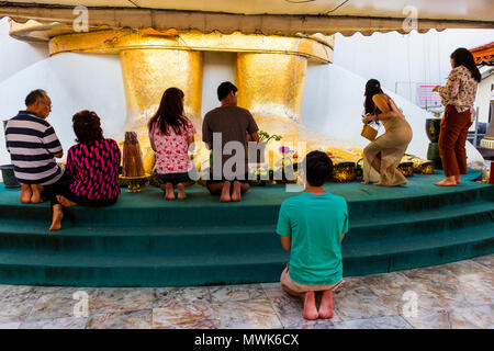 Believers praying in front of the feet of a Big Standing Buddha in Wat Intharawihan Temple Stock Photo