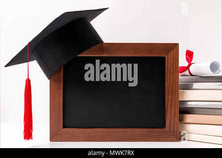 Diploma on stack of books, empty blackboard with academic cup isolated on white Stock Photo
