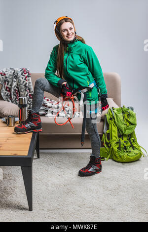 beautiful smiling climber in helmet with climbing equipment at home Stock Photo