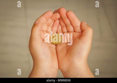 Child holding ten euro cents coin in his hands. Pocket money concept, first money earned stock image. Stock Photo