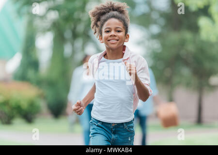 portrait of smiling african american little girl running in park Stock Photo