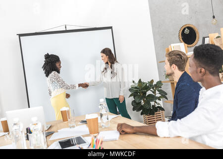 side view of multiethnic young businesswomen shaking hands during business meeting Stock Photo