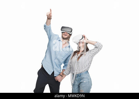 Happy young couple wearing virtual reality headsets and holding hands isolated on white Stock Photo