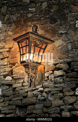 Magical romantic shimmer of vintage old metallic lantern hanging on an ancient stone wall Stock Photo