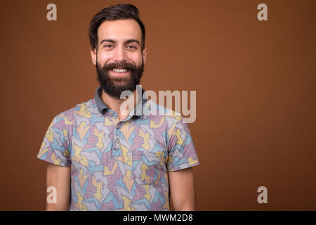 Young handsome bearded Persian man against brown background Stock Photo