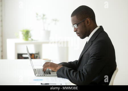 Focused black worker working at laptop at company workplace Stock Photo