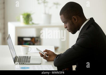 Focused African American checking phone email in office Stock Photo
