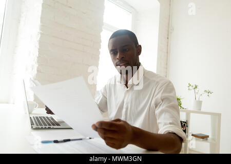 Focused black worker analyzing company statistics reading papers Stock Photo