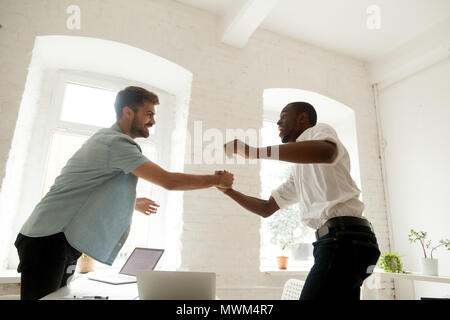 Excited office workers handshaking celebrating business success Stock Photo