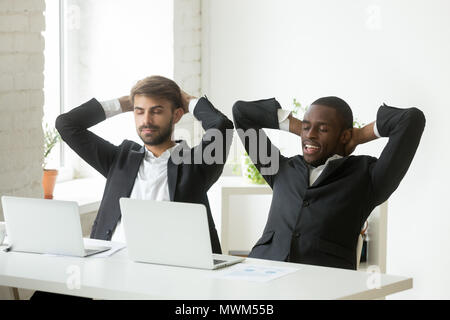 Satisfied multiethnic workers relaxing in chairs after successfu Stock Photo