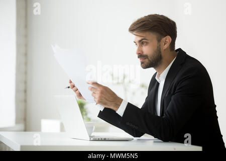 Happy businessman holding papers reading financial statistics Stock Photo
