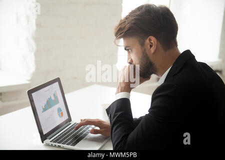 Thoughtful entrepreneur looking at laptop thinking about solving Stock Photo