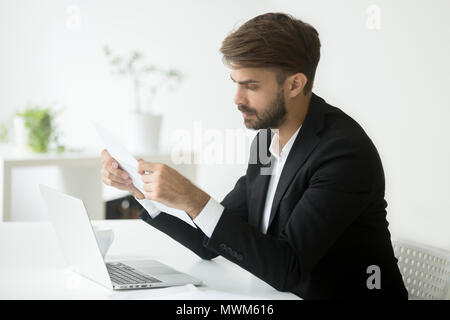 Serious businessman reading papers analyzing business strategies Stock Photo