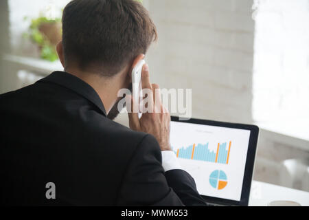 Businessman multitasking, talking on phone while working at lapt Stock Photo