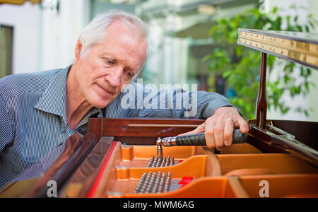 Elderly music instrument technician tuning a piano keyboard. Stock Photo