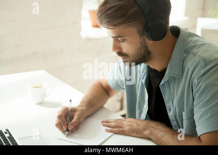 Concentrated worker in headphones watching webinar noting import Stock Photo