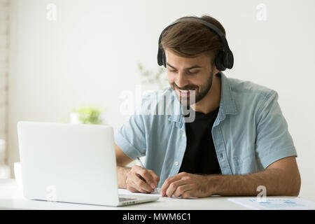 Worker in headphones listening to audio course writing important Stock Photo