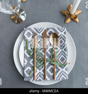 flat lay with old fashioned cutlery, napkin, green plant on plates on tabletop Stock Photo
