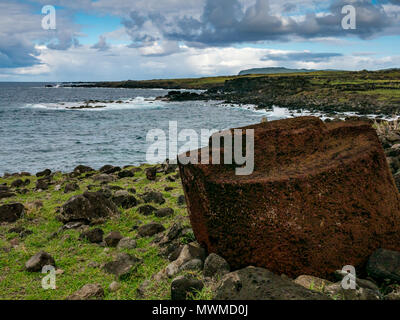 South coast Easter Island, Rapa Nui, Chile, with red volcanic scouria rock top knot carved stone in foreground, and view of extinct volcano Rano Kau Stock Photo