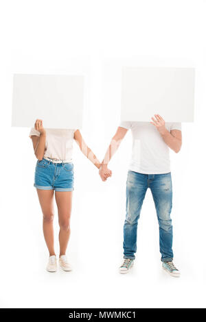 'Attractive young couple holding hands and hiding faces by blank banners, isolated on white Stock Photo