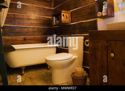 Bathroom with white porcelain claw foot bathtub and high back toilet inside an old circa 1850 cottage style fieldstone home Stock Photo