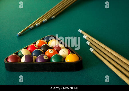 top view of billiard balls in a triangle with several cue sticks Stock Photo