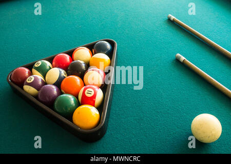 two cue sticks and billiard balls arranged in a triangle Stock Photo