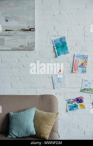 close up view of empty childish room with sofa and colorful drawings on white brick wall Stock Photo