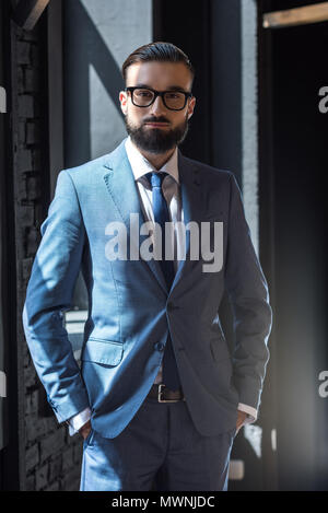 handsome confident businessman in grey suit looking at camera Stock Photo