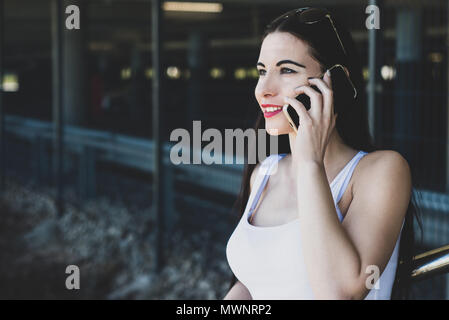 A beautiful woman relaxes by talking on the phone. The girl is resting while sitting on the ground and conducting a conversation. Concept lifestyle. Stock Photo