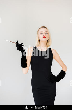 attractive stylish blonde woman in black dress with cigarette isolated on white
