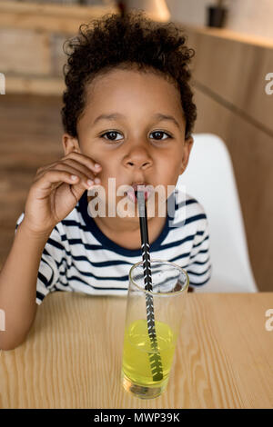 cute african american boy drinking juice and looking at camera in cafe Stock Photo