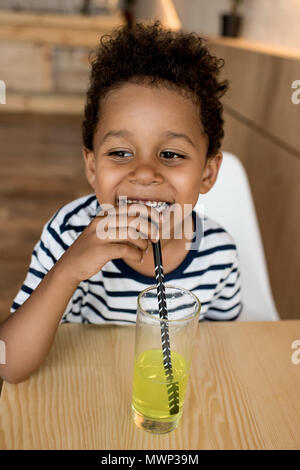 adorable smiling african american boy drinking juice in cafe Stock Photo