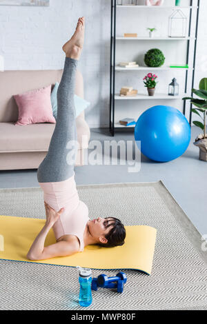 beautiful young woman practicing yoga in Supported Shoulder Stand (Salamba  Sarvangasana) at home Stock Photo - Alamy