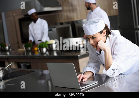 attractive chef using laptop at restaurant kitchen Stock Photo