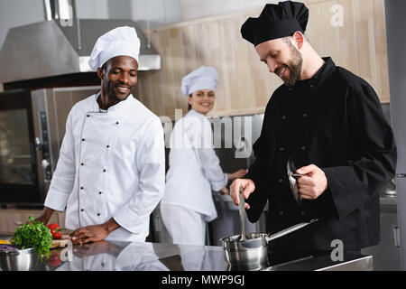 smiling multicultural chefs cooking together at restaurant kitchen Stock Photo