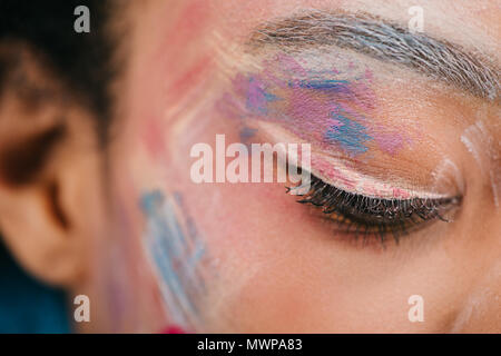 cropped shot of woman with colorful strokes on face with closed eye Stock Photo