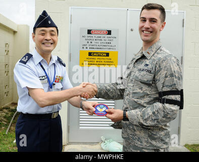 Japan Air Self-Defense Force Col. Riichi Furugaki, JASDF Air Staff College director of education department, presents a JASDF Air Staff College patch to U.S. Air Force 2nd Lt. William Holmquist, 18th Logistics Readiness Squadron fuels operations officer, April 27, 2017, at Kadena Air Base, Japan. The 18th LRS petroleum, oils and lubricants flight maintains relationships with fellow JASDF members by hosting frequent tours of their facilities. Stock Photo