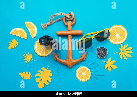 Sea travel background with sunglasses, binoculars, anchor, compass and tropical leaves on a bright blue background. Summer vacation concept with copy space Stock Photo