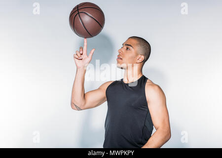 african american sportsman spinning basketball ball on finger Stock Photo