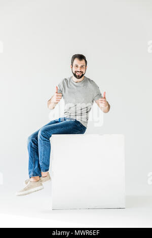 handsome young man showing thumbs up and smiling at camera isolated on white Stock Photo